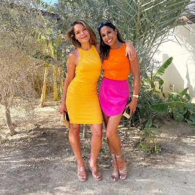 Taniya is wearing an orange top with pink skirt whereas, Sabrina is wearing a yellow dress